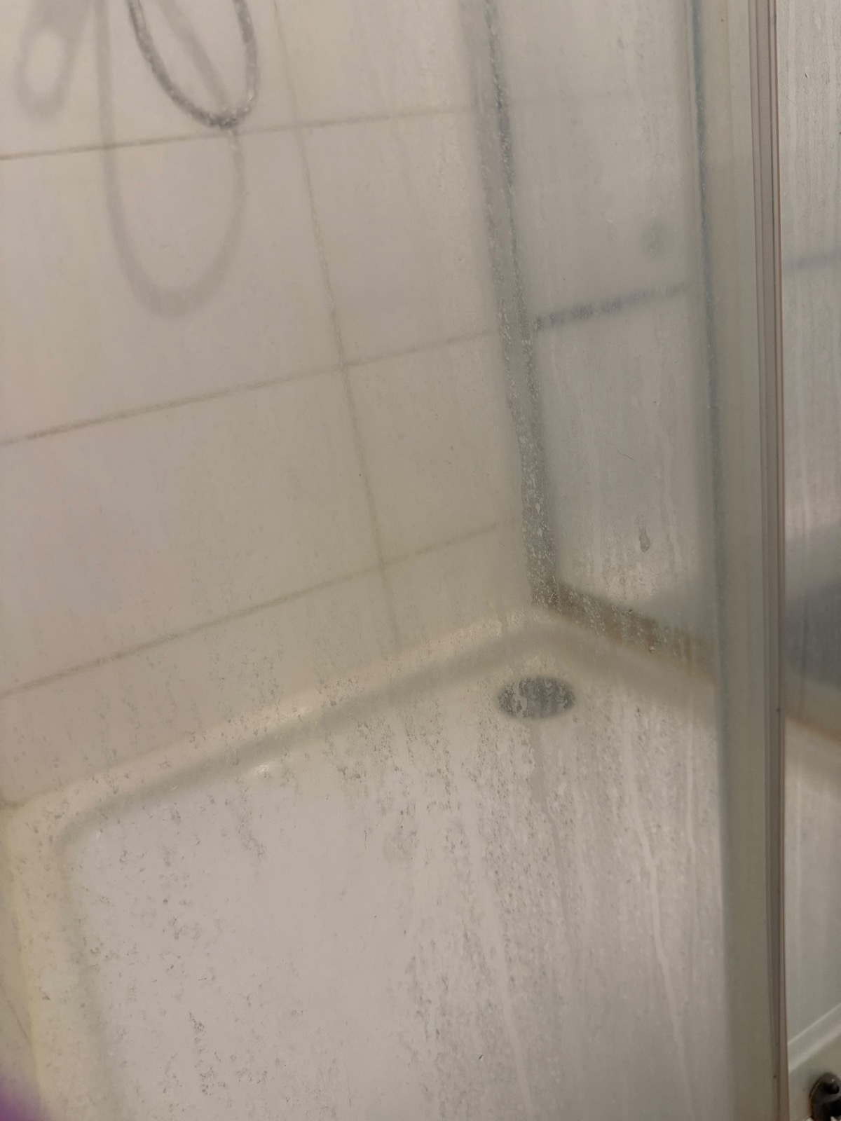 Verkalkte Dusche mit beschlagenem Glas und schmutziger Duschwanne vor der Reinigung