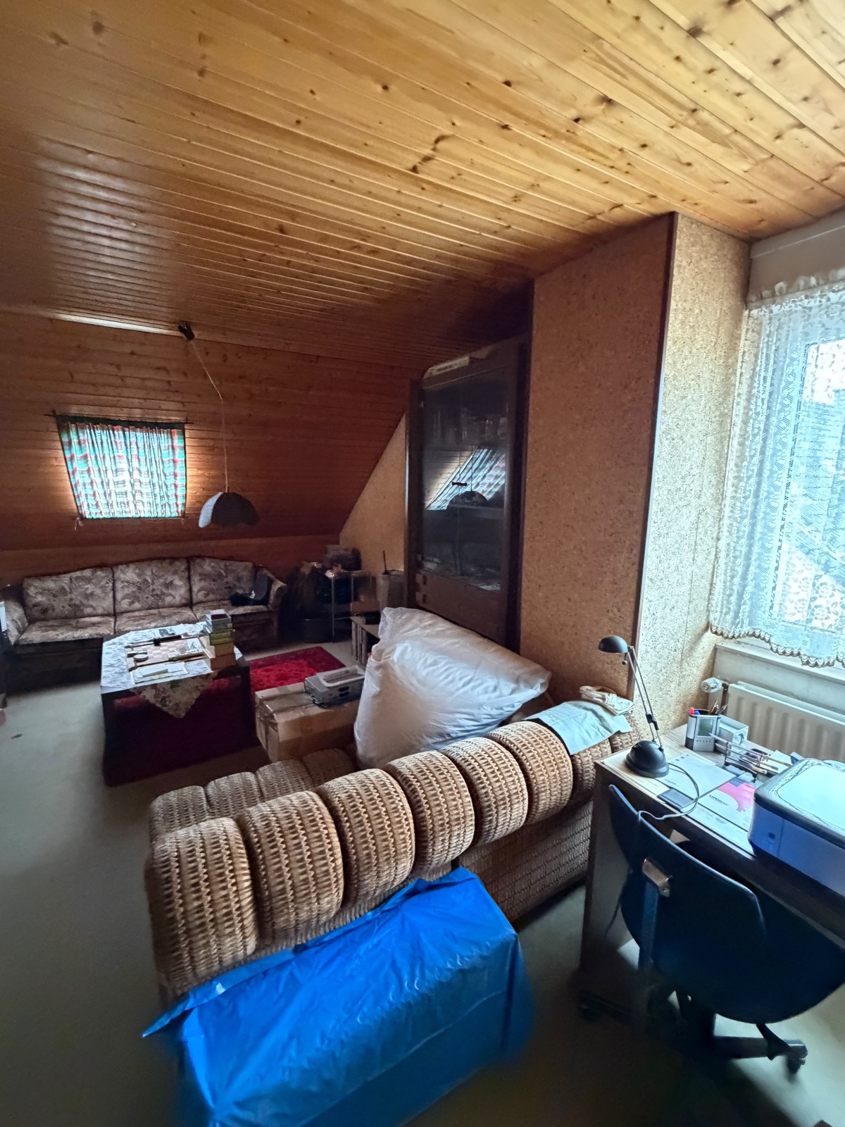 Vollgestelltes Dachzimmer mit Rattanmöbeln vor der Wohnungsauflösung