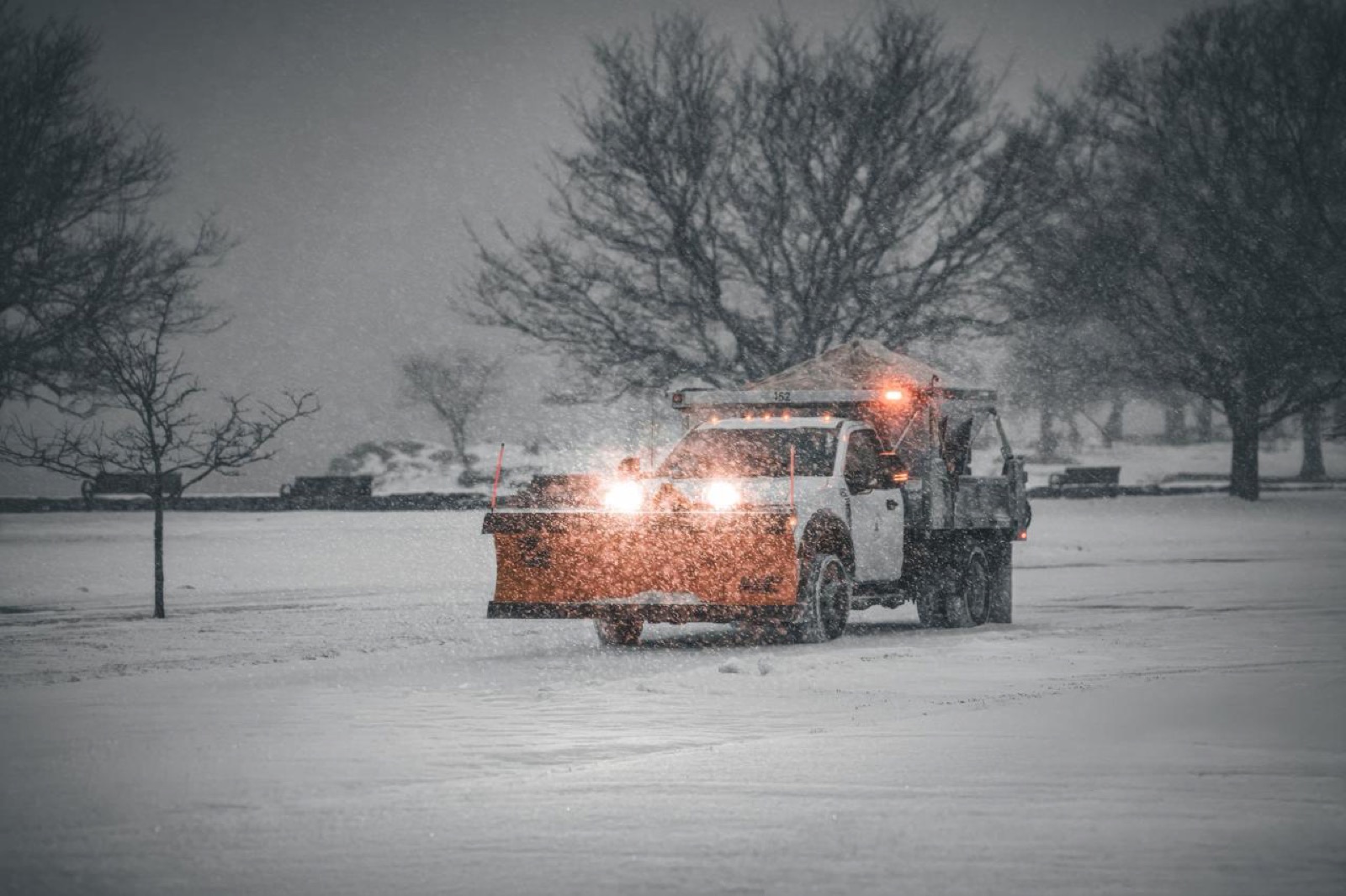 Räumfahrzeug mit Schneepflug bei starkem Schneefall im Winterdienst